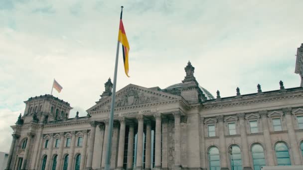 In Zeitlupe weht die Deutschlandfahne vor dem Hintergrund des zentralen Eingangs zum Gebäude des Bundestages im Zentrum der Hauptstadt Berlin. vor blauem Hintergrund — Stockvideo