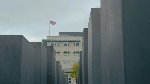 Βερολίνο, Γερμανία-2018 Οκτωβρίου: αστέρια και ρίγες της αμερικανικής σημαίας στο κτίριο της αμερικανικής πρεσβείας στο Βερολίνο της Γερμανίας, με φόντο το μνημείο του Ολοκαυτώματος, αργή κίνηση — Αρχείο Βίντεο