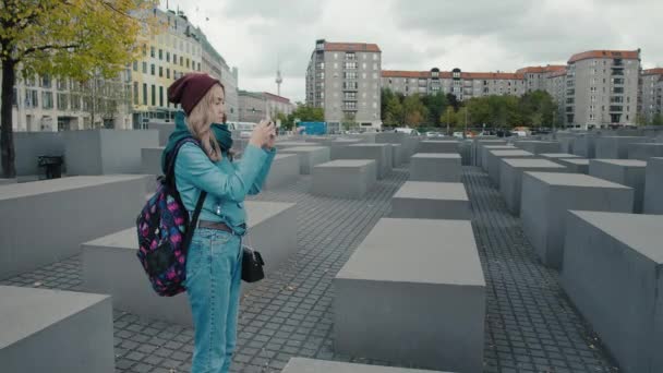 Berlin, Almanya - Ekim 2018: Sonbaharda Berlin'in merkezinde sırt çantası olan Yavaş Hareket Beyaz kız turist. Bir akıllı telefonda Avrupa'da Öldürülen Yahudiler için Anıt bir fotoğraf yapar. Inç — Stok video