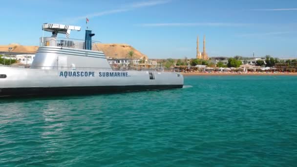 SHARM EL SHEIKH, EGYPTE - DÉCEMBRE 2018 : Des marins sur un sous-marin gris scientifique ou militaire sur fond de station balnéaire tropicale et de mosquée musulmane. Mouvement lent — Video