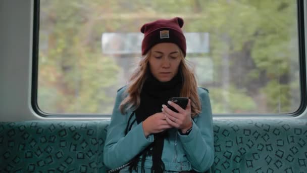 Ung vit flicka sitter i en tunnelbana tåg bil, använder telefonen, läser ett meddelande, och blir rädd. Hon är rädd. Hon är uttråkad. Hon gäspar. Långsamma rörelser — Stockvideo