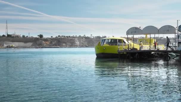 Sharm El Sheikh, Egypte-december, 2018: grote gele toeristische onderzeeër voor zee wandelingen staat op de pier in de baai. Niet-herkend personeel lopen langs de Pier — Stockvideo