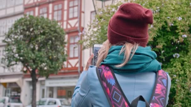 Молодая туристка фотографирует на смартфоне историческую часть немецкого города. Медленное движение, крупный план — стоковое видео