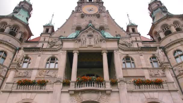 Hannover, Németország-október 2018: fenséges középkori vár két torony oldalán. Az erkélyeken vörös virágot ültetnek. Panoráma függőleges. A bejárat közelében van két nő. Zöld tetők, nagy — Stock videók