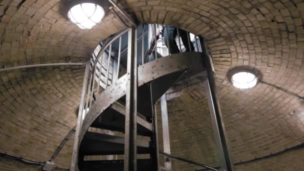 Točité schodiště ve starém podkrovním hradu s cihlovými stěnami, podél nichž neznámý muž s deštníkem. Odchod. Zpomaleně — Stock video