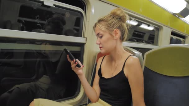 Hermosa mujer turista caucásica monta el tren a través del túnel. Afuera las luces de la ventana se mueven. Utiliza el mensaje de huellas de teléfonos móviles. Está triste. Moción lenta — Vídeo de stock