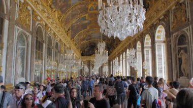 Versailles, Paris, Fransa- Ağustos 2018: Kraliyet sarayının ana salonunda çok sayıda turist. Ziyaretçiler simge yapının fotoğraflarını çekerler. Büyük avizeler tavandan asılır. Yavaş Çekim