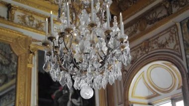Versailles, Paris, Fransa- Ağustos 2018: Kraliyet sarayının lüks iç mekanı. Ortaçağ avize, arka planda büyük nadir resimler ve freskler. Boyalı altın duvarlar. Yavaş Çekim