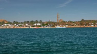 Güneşli bir günde yaz aylarında mavi güzel denizde Hareket sürat teknesi. Palmiye ağaçlarının ve tatil otellerinin arka planında. Uzaktan bir minare ve cami görülebilir. Yavaş Çekim