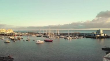 Havadan ateş. Marina, Atlantik Okyanusu kıyısında küçük bir balıkçı kasabasında bir liman. Gün batımında çok sayıda tekne, yat ve tekne. Merkezde kırmızı yelkenli bir yat var. Kavramı