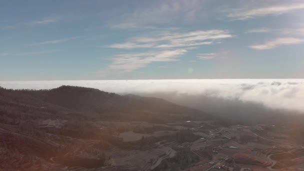 Tiro aéreo. Voando em um dia ensolarado e claro sobre nuvens volumétricas de trovoada de textura. Abaixo fazendas em cascata e edifícios externos. Topografia incomum da terra. Tenerife, Ilhas Canárias, Espanha — Vídeo de Stock