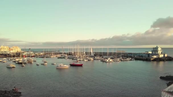 Un disparo aéreo. Marina, un puerto en un pequeño pueblo pesquero a orillas del Océano Atlántico. Un gran número de barcos, yates y barcos al atardecer. En el centro hay un yate de vela rojo. El concepto de — Vídeo de stock