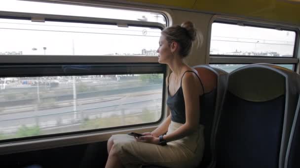 Belle touriste caucasienne traverse Paris en métro et regarde par la fenêtre. Dans la fenêtre, vous pouvez voir la banlieue industrielle de Paris. Mouvement lent — Video