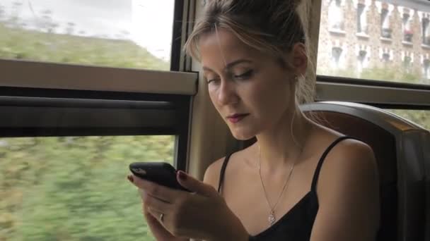 Hermosa mujer turista caucásica monta el tren subterráneo. Usa un teléfono móvil mirándolo bien balanceándose. Moción lenta, primer plano — Vídeo de stock