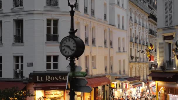 Montmartre, París, FRANCIA Agosto 2018: Gran reloj en un poste de luz. Turistas caminando por las calles nocturnas de la capital. Moción lenta — Vídeos de Stock