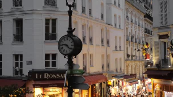 Montmartre, Paříž, Francie-srpen 2018: velké hodiny na lampu. Turisté se sem chodí po večerních ulicích hlavního města. Zpomaleně