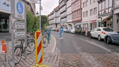 Hannover, Almanya - Ekim 2018: Sırt çantası yla dolaşan ve sokakta yürüyen genç kadın turist. Küçük evlerin olduğu sokak. Yavaş Çekim