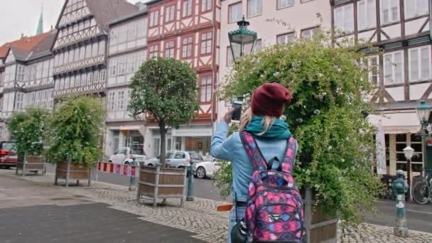 Молодая туристка фотографирует на смартфоне историческую часть немецкого города. Slow Motion — стоковое видео