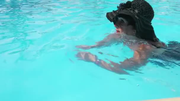 Καυκάσια ηλικιωμένη γυναίκα που κολυμπάει σε μια γαλάζια πισίνα σε ένα ξενοδοχείο. Η έννοια του υγιεινού τρόπου ζωής, η δραστηριότητα στη συνταξιοδότηση. Αργή κίνηση — Αρχείο Βίντεο