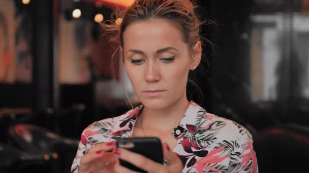 Kaukasische jonge vrouw maakt gebruik van smartphone terwijl zittend in een restaurant. Slow Motion — Stockvideo