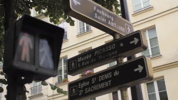Παρίσι, Γαλλία-2018 Αυγούστου: φώτα κυκλοφορίας πεζών στη διασταύρωση των δύο δρόμων. Στις πινακίδες των σπιτιών, πινακίδες δρόμου. Κλαδιά από πράσινα δέντρα. Αργή κίνηση — Αρχείο Βίντεο