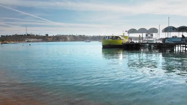 Deniz yürüyüşleri için büyük sarı turist tekne koyda iskelede maliyeti. Tanınmayan personel iskele boyunca yürüyor — Stok video