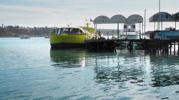 Šarm el Šejch, Egypt-prosinec, 2018: Velká žlutá turistická ponorka pro mořské procházky stojí na molu v zálivu. Neznámý personál pěšky po molu — Stock video