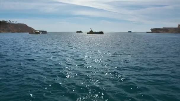 Navigatie schepen in de zee. De beweging van de gele toeristische boten-bathyscaphes in de open zee, tegen de achtergrond van pleziervaartuigen en rotsachtige kaap peps. Slow Motion — Stockvideo