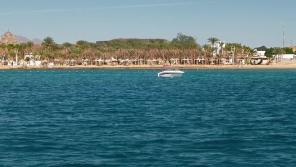 Turist höghastighetsbåt på bakgrunden av det blå havet och stranden av palmer. I fjärran, en stor arabisk muslimsk moské och två minareter. Slow motion, närbild — Stockvideo