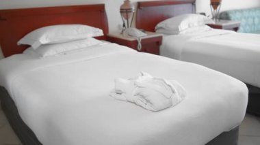 tanınmayan yetişkin yaşlı kadın koyar ve bir otel odasında bir yatakta beyaz bir bornoz yanında mükemmel beyaz bir havlu doğrultucu. Yavaş Çekim