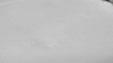 Beyaz bornozla tanınmayan yetişkin yaşlı kadın bir otel odasında yatağa beyaz bir havlu koyar. Yavaş Çekim, Yakın Çekim