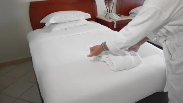 Unrecognized adult senior woman puts and towel next to a white robe on the bed. The concept of cleaning the apartment. Slow Motion — Stock Video