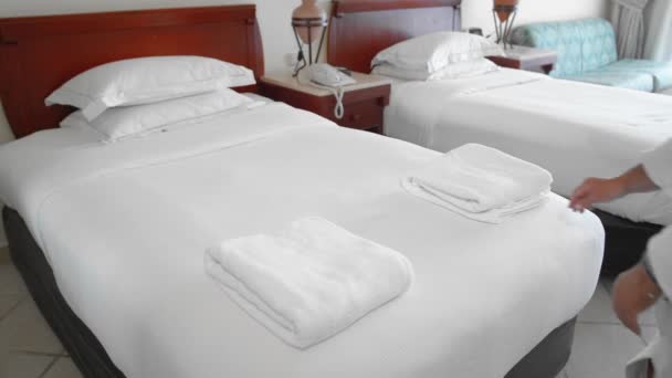 Nierozpoznany dorosły starszy kobieta podnosi biały ręcznik leżący na łóżku w pokoju hotelowym. Koncepcja obsługi i sprzątania w hotelu. Zwolnionym — Wideo stockowe