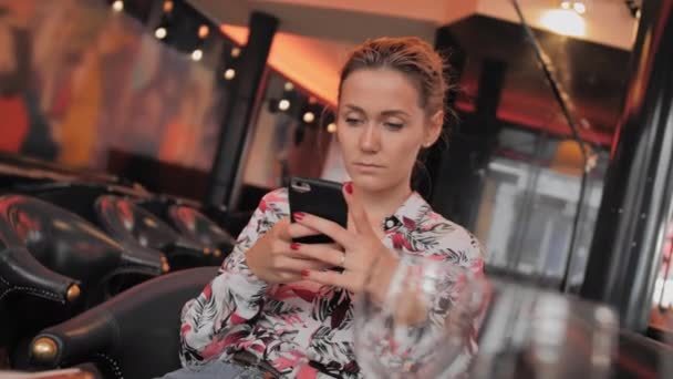 Jonge vrouwelijke Fransen maakt gebruik van sociale netwerken om te communiceren met een mobiele telefoon. Zit in een restaurant te wachten op uw bestelling. Slow Motion — Stockvideo