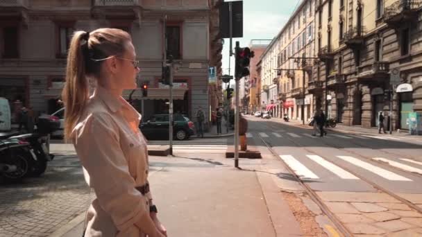 Milano, İtalya - Mayıs 2019: İtalyan moda başkentinin tarihi merkezinde alışveriş yaptıktan sonra çantasıyla ayakta duran Beyaz bir kadının portresi. Yavaş çekim — Stok video