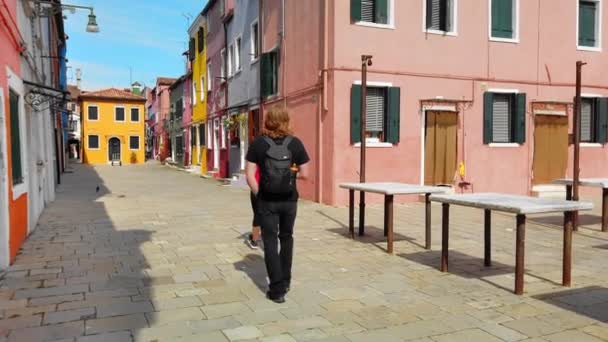 Burano, Βενετία, Ιταλία-2019 Μαΐου: δύο μη αναγνωρίσιμες τουρίστες περπατούν γύρω από τη μεσαιωνική πόλη. Πολύχρωμα σπίτια. Αργή κίνηση — Αρχείο Βίντεο