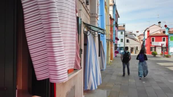 Burano, Venedik, İtalya - Mayıs 2019: Geleneksel İtalyan sokağında erkek ve kadın aşık tanınmayan çift. Renkli evlerin arka planına karşı. Yavaş çekim. — Stok video