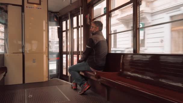 Milano, Italien-maj 2019: en typisk italiensk man rider i en retro spårvagn medan du sitter på en träbänk. Begreppet ensamhet. Slow motion — Stockvideo