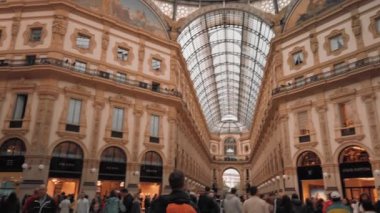 Milano, İtalya - Mayıs 2019: Çok sayıda turist ve iç galeri Vittorio Emanuele. Butiklerin işaretleri, alışveriş konsepti ve pahalı lüks mağazalar. Panorama. Yavaş çekim, dolly çekim