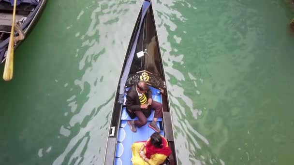 VENEZIA - Maggio 2019: gondola veneziana. Una famiglia indiana multirazziale di turisti che passeggiano su una gondola attraverso i canali della città. Vista dall'alto. Rallentatore — Video Stock