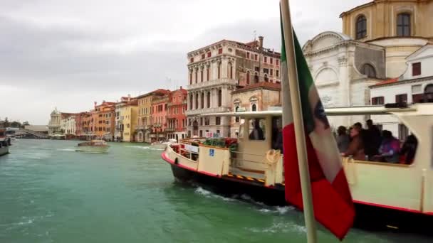 VENISE, Italie - Mai 2019 : Vue sur la ville depuis le grand canal. Au centre se trouve le drapeau de l'Italie sur le mât d'un bateau. Un vaporetto passe. Mouvement lent — Video