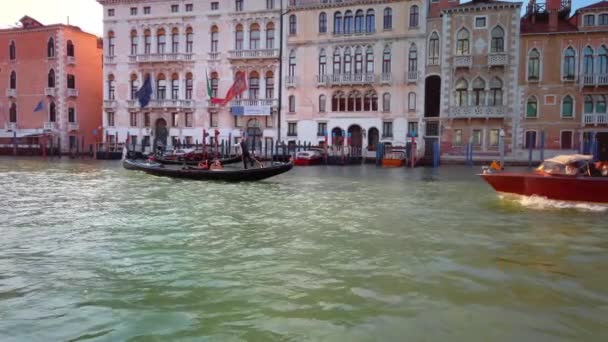 Venetië, Italië-mei 2019: Brown Venice taxi Boat overneemt een gondel die langs een Canal Grande loopt. Zonsondergang Slow Motion. — Stockvideo