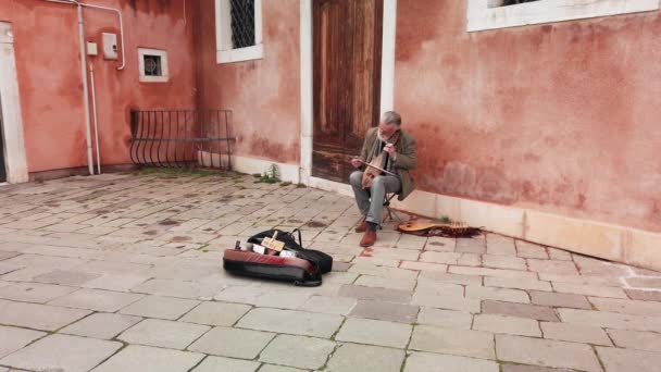 Venedik, İtalya - Mayıs 2019: yaşlı kör adam yay lı alışılmadık bir ortaçağ müzik aleti çalıyor. İtalya'nın sokağında. Yavaş çekim — Stok video