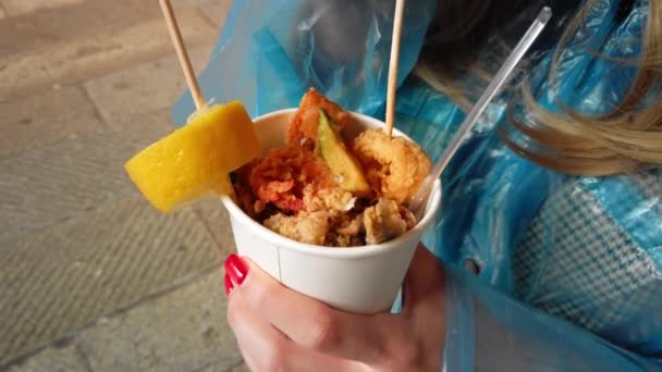 Venetië, Italië-mei 2019: vrolijk glimlachend meisje eet gegrilde zeevruchten op de vismarkt van Venetië. Regenachtig weer. Slow Motion — Stockvideo