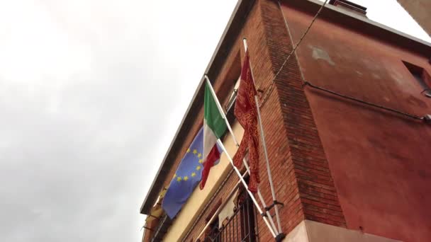 Murano, Wenecja, Włochy-maj 2019: flagi Unii Europejskiej, Włochy i miejska flaga Wenecji wahadłowe na wietrze na maszcie w domu w stylu włoskim. Zwolnionym — Wideo stockowe