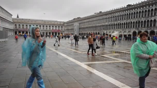 Benátky, Itálie – květen 2019: spousta turistů v deštivém počasí v deštných kabátech. Používejte telefony Smartphone na náměstí sv. Zpomaleně — Stock video