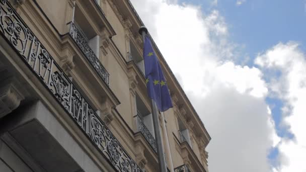 Flaga Unii Europejskiej na tle typowego francuskiego domu w Paryżu. W ramce błękitnego nieba i białych chmur. Zwolnionym — Wideo stockowe