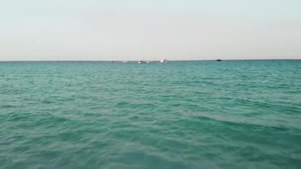 巴勒莫，西西里岛，意大利 - 2019年8月：快乐的女孩挥手站在海里。飞过水面。背景中无法识别的游艇。日落时间。空中无人机射击. — 图库视频影像