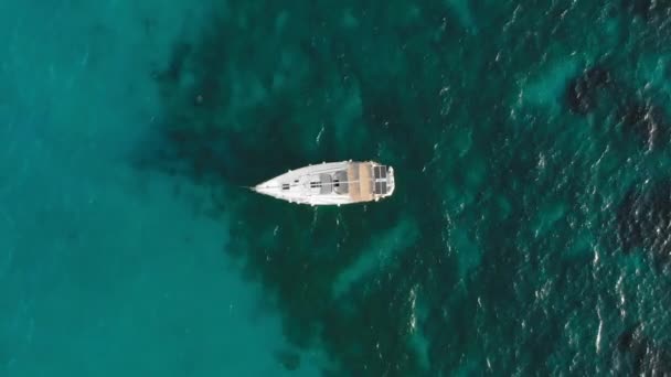 Weiße Segeljacht mit Sonnenkollektoren auf dem Deck. vor dem Hintergrund des türkisfarbenen Ozeans. das Konzept der teuren Entspannung und des Umweltschutzes. Drohnenschuss aus der Luft. — Stockvideo