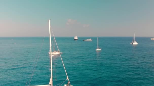 Bílé jachty a neznámé lidi, kteří na nich odpočívají. Na pozadí modrého oceánu. Konec stěžně. Pojem dovolené na moři, luxusní dovolená. Letecká střela — Stock video